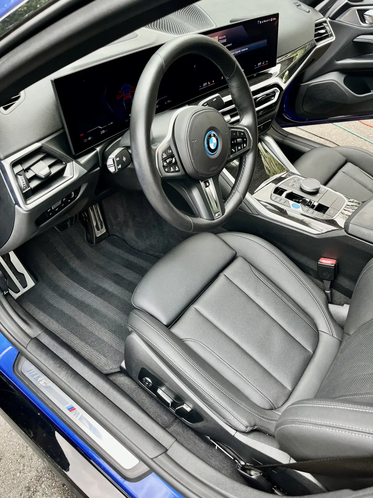 BMW driver footwell with clean, dry carpet and mat next to a black leather seat