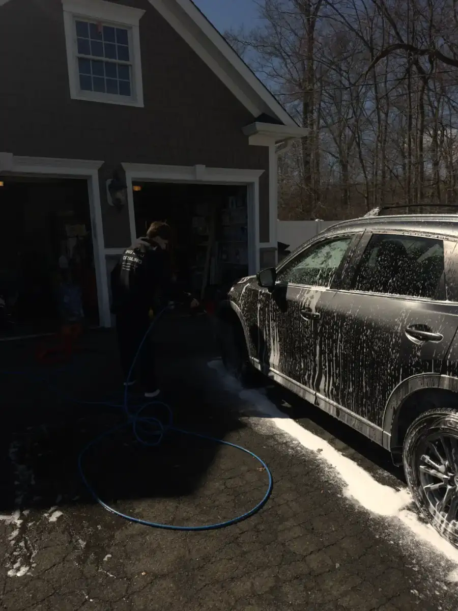 Christian, GNG Auto Detail co-founder, pressure washing a car exterior in Morris County, NJ
