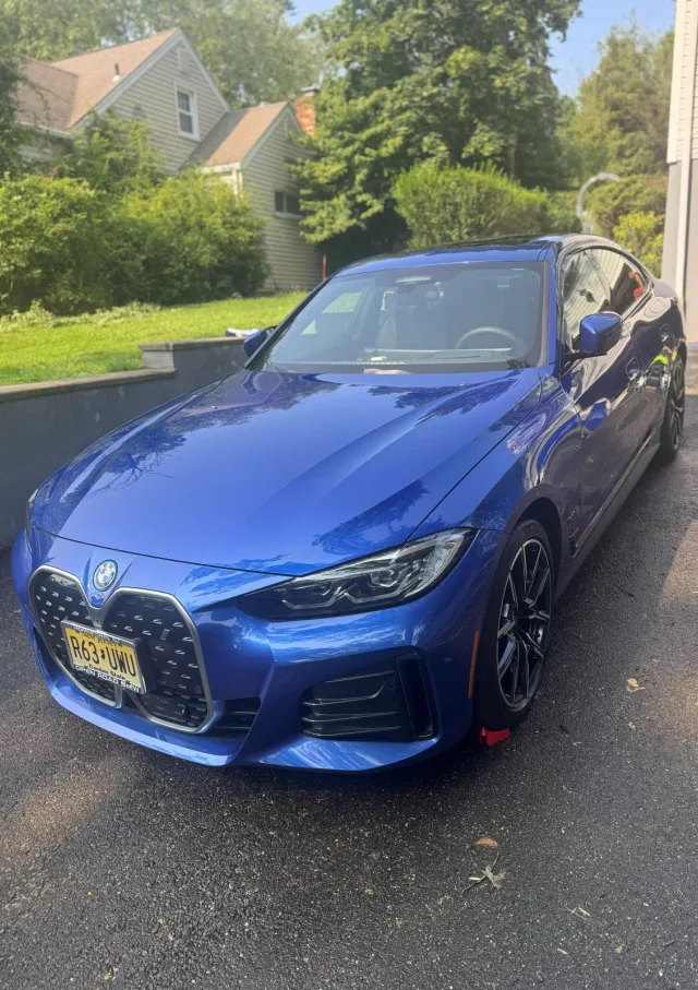 Blue BMW 4 Series after an exterior detail, paint and wheels glossy in a Morris County driveway