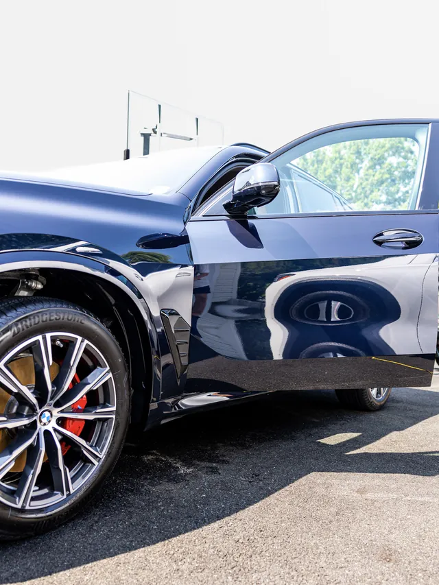 Midnight blue BMW X5 with the door open, paint so glossy it reflects the wheel