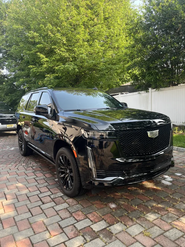 Black Cadillac Escalade with a deep gloss after an exterior detail on a paver driveway