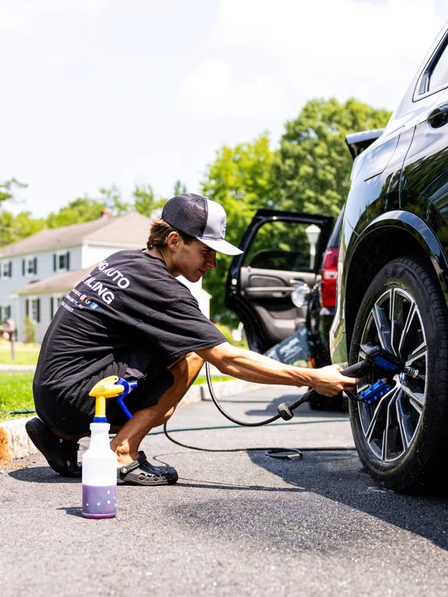 Christian detailing a BMW wheel with a brush during a mobile exterior detail in Morris County