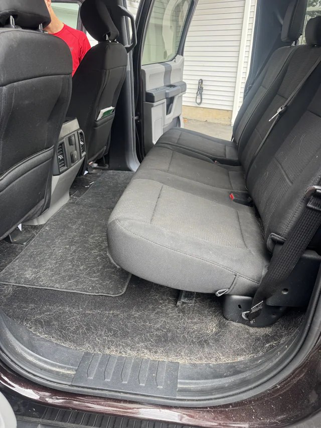 Vehicle rear seating area covered in pet hair before GNG interior detailing